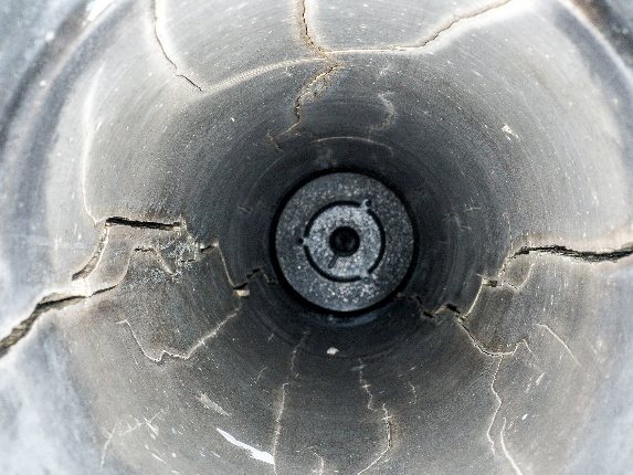 Looking down a full-scale test bore after firing: radial fractures run outward from the hole through the surrounding block.