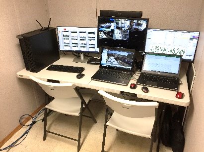 Remote control room with monitors showing site cameras and control screens.